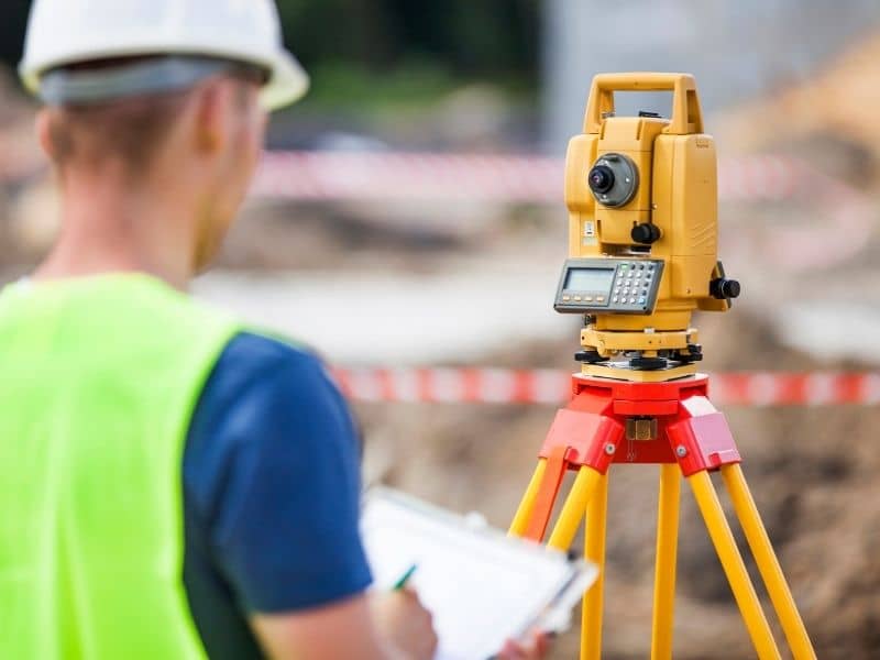 Surveyor using a total station during an ALTA survey to support commercial property due diligence.
