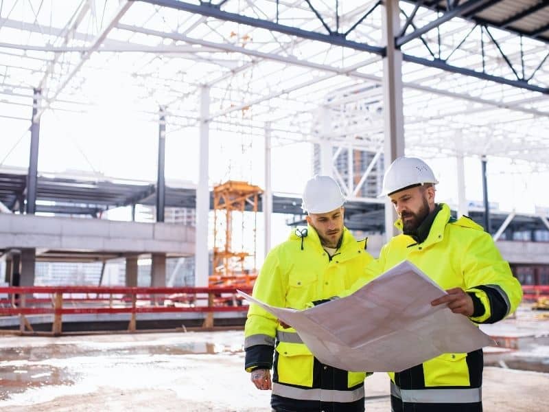 Construction professionals reviewing site plans inside a commercial development project for ALTA survey boundary and ownership verification.