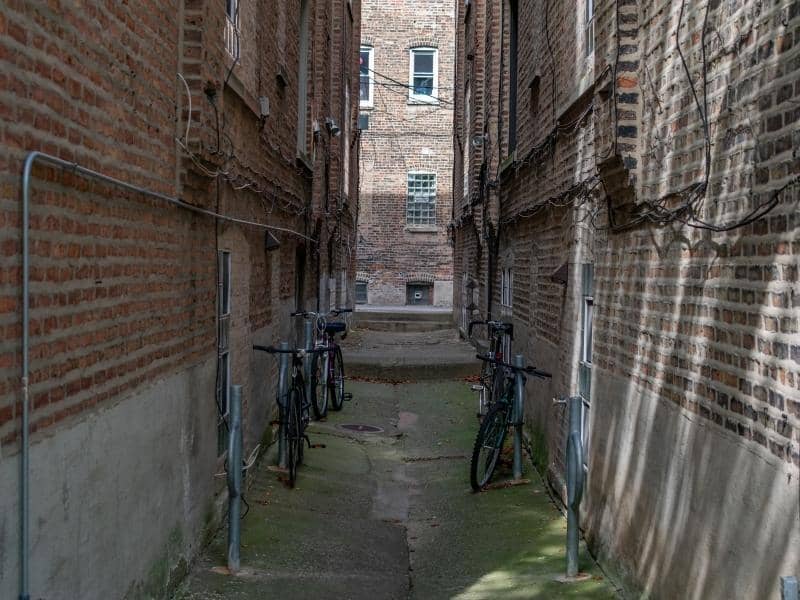 Narrow urban alley between brick buildings reviewed for land surveying, rear lot access, and shared property use.